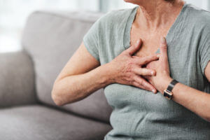 A person with chronic obstructive pulmonary disorder symptoms is struggling to breathe, sitting upright with their hands on their chest.